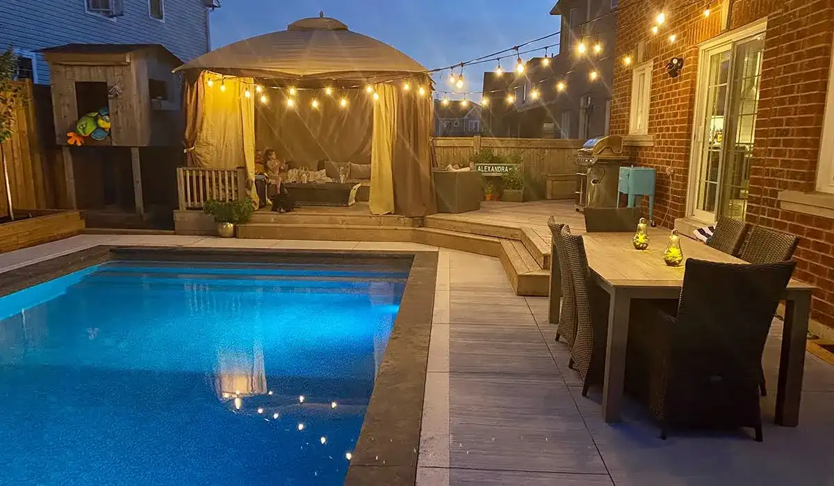 Pool and pavilion lit with string lights at dusk