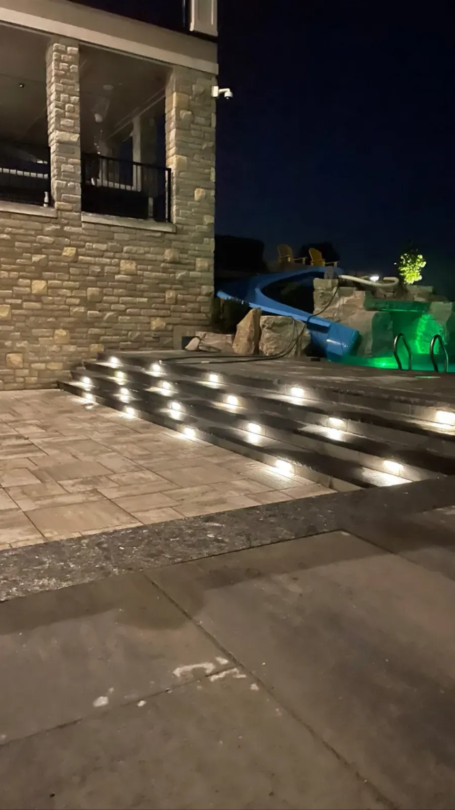 A grotto pool and slide lit up after dark