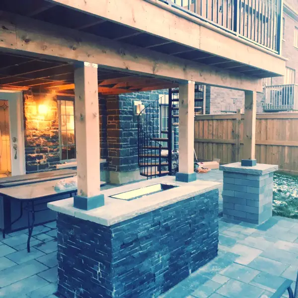 Outdoor kitchen and bar on the stone-clad lower patio