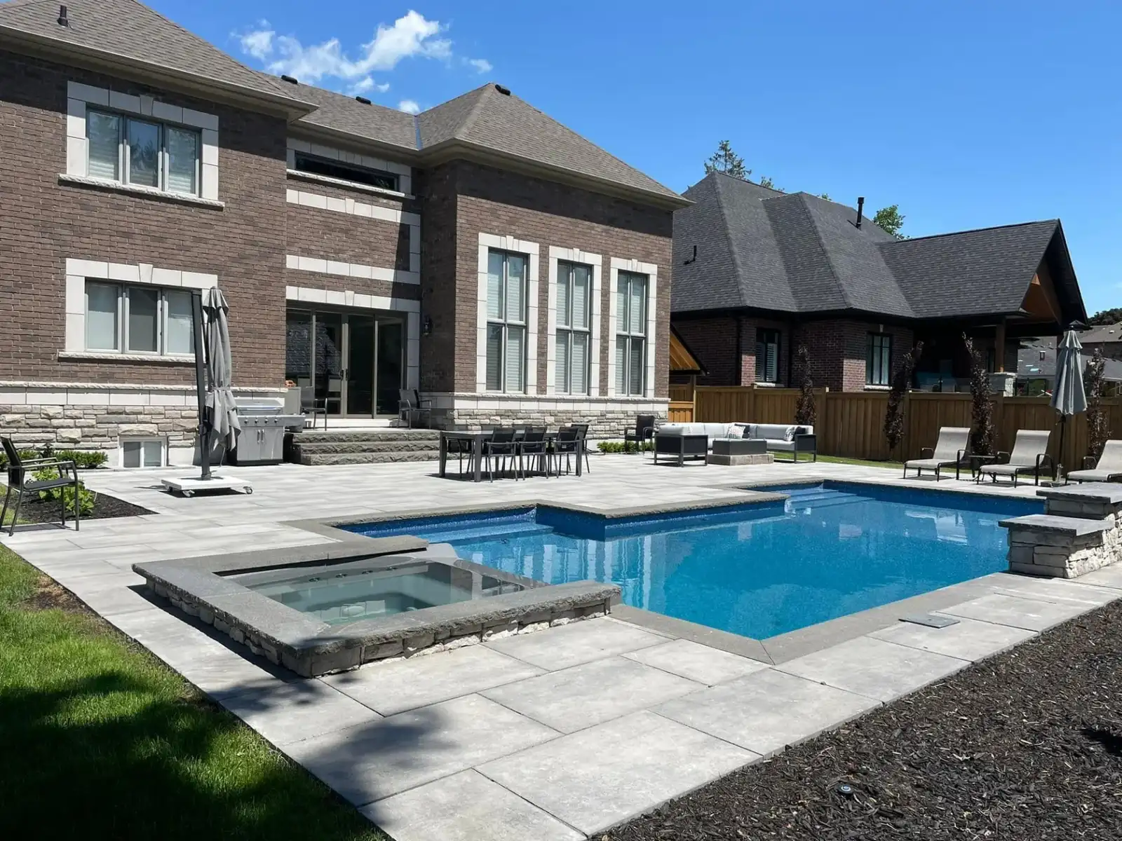 Rectangular pool with a raised spa beside a brick home