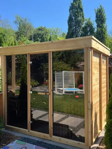 Glass-front cedar sauna cabin in the backyard