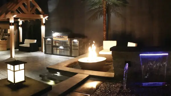Fire bowl burning beside a lit pool at night