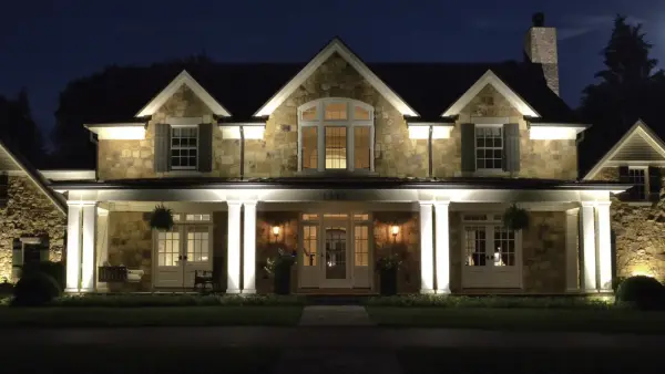 A stone home lit from the garden at night