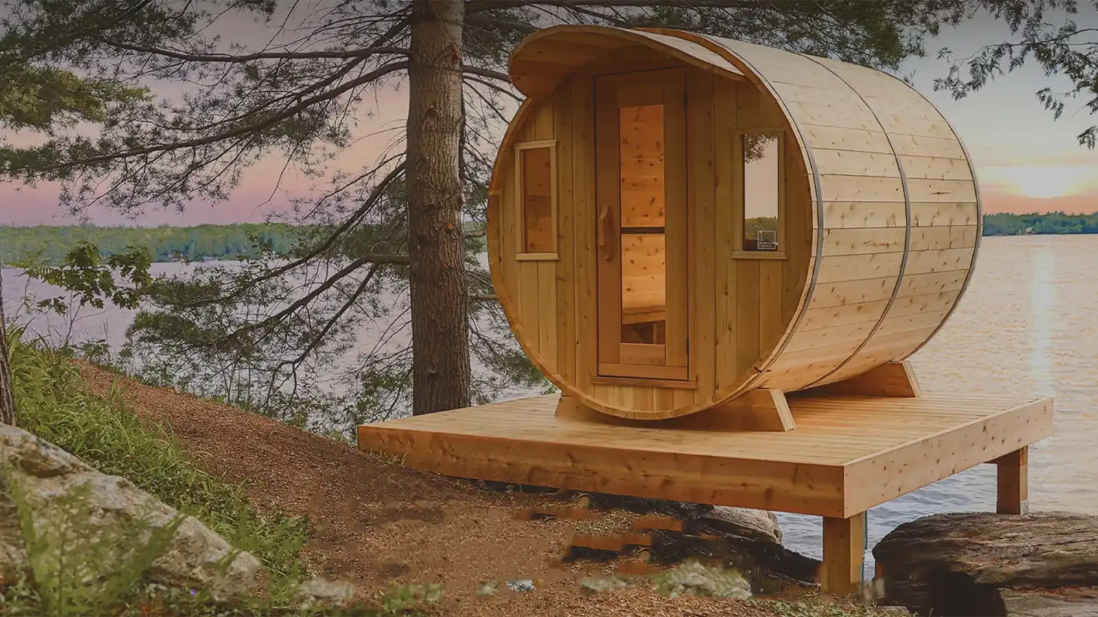 Cedar barrel sauna set on a stone pad in the trees